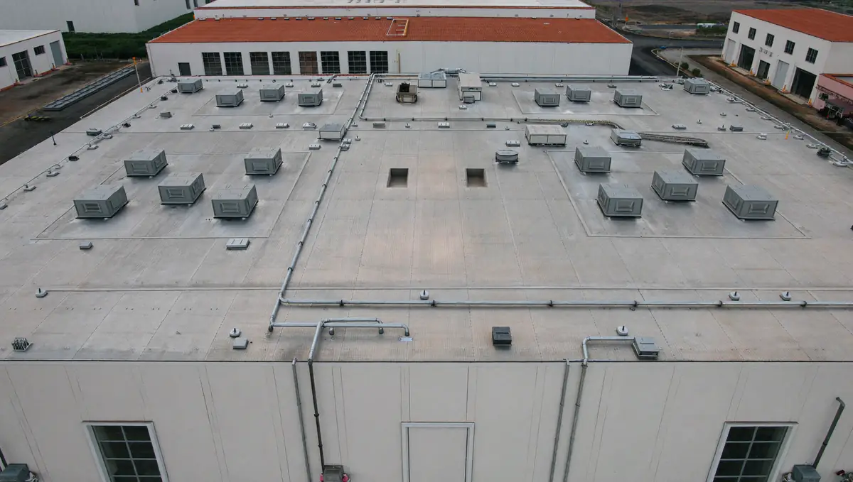 Aerial view of a large flat industrial warehouse roof with skylights and rooftop ventilation units