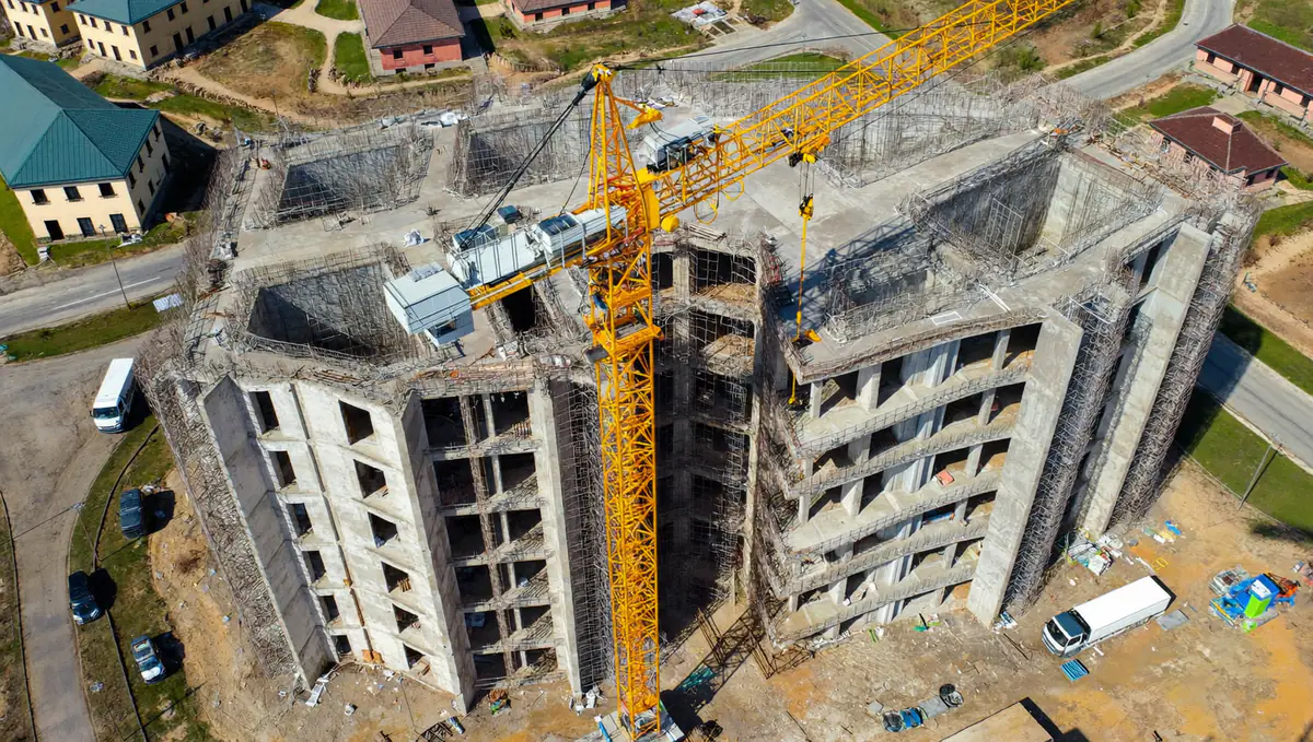 Aerial view of a residential building under construction with a tower crane and scaffolding