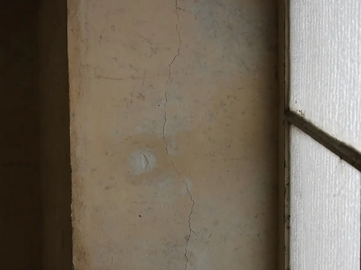 Crack running diagonally through plaster beside a window