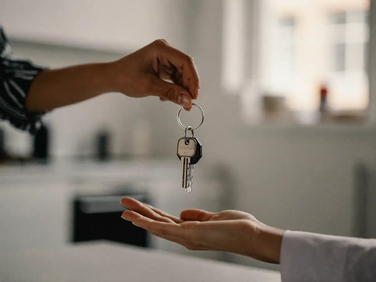 Hands handing over a set of keys with a blurred apartment interior behind